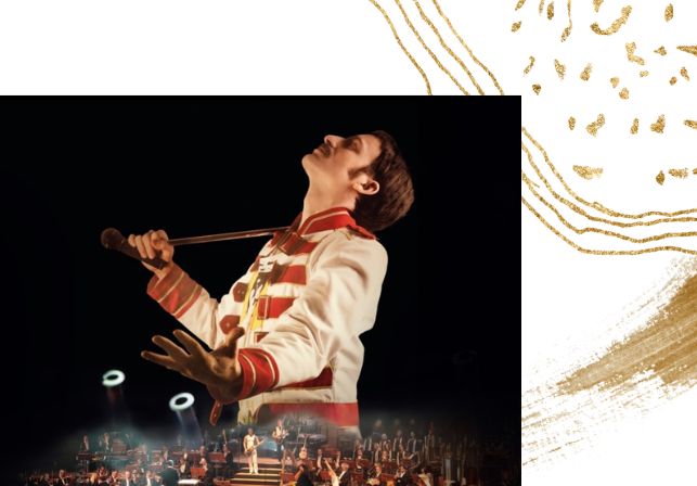 Ein Mann ist gekleidet wie der Musiker Freddie Mercury und schaut mit gesschlossenen Augen nach oben. Am unteren Bildbereich ist eine Bühne mit Musikern eingeblendet.
